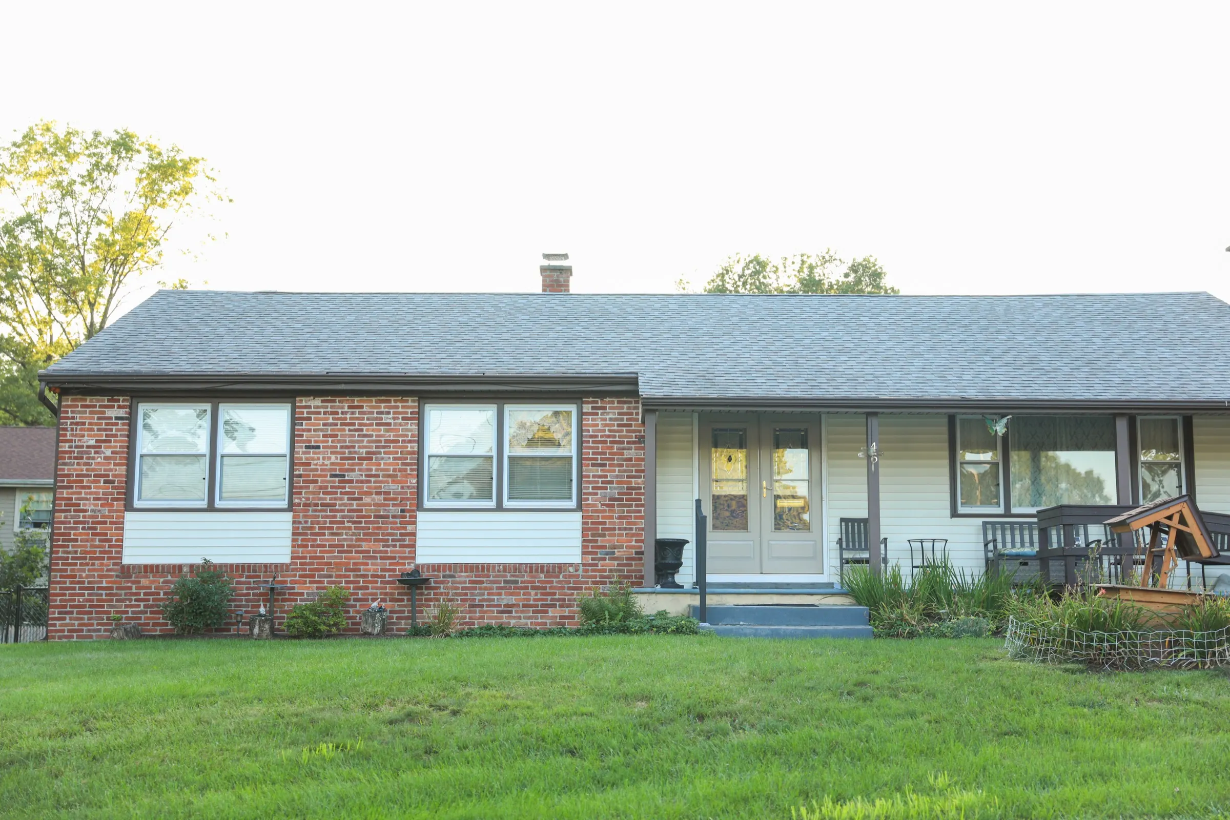 Brick ranch house with a front porch under an overcast sky