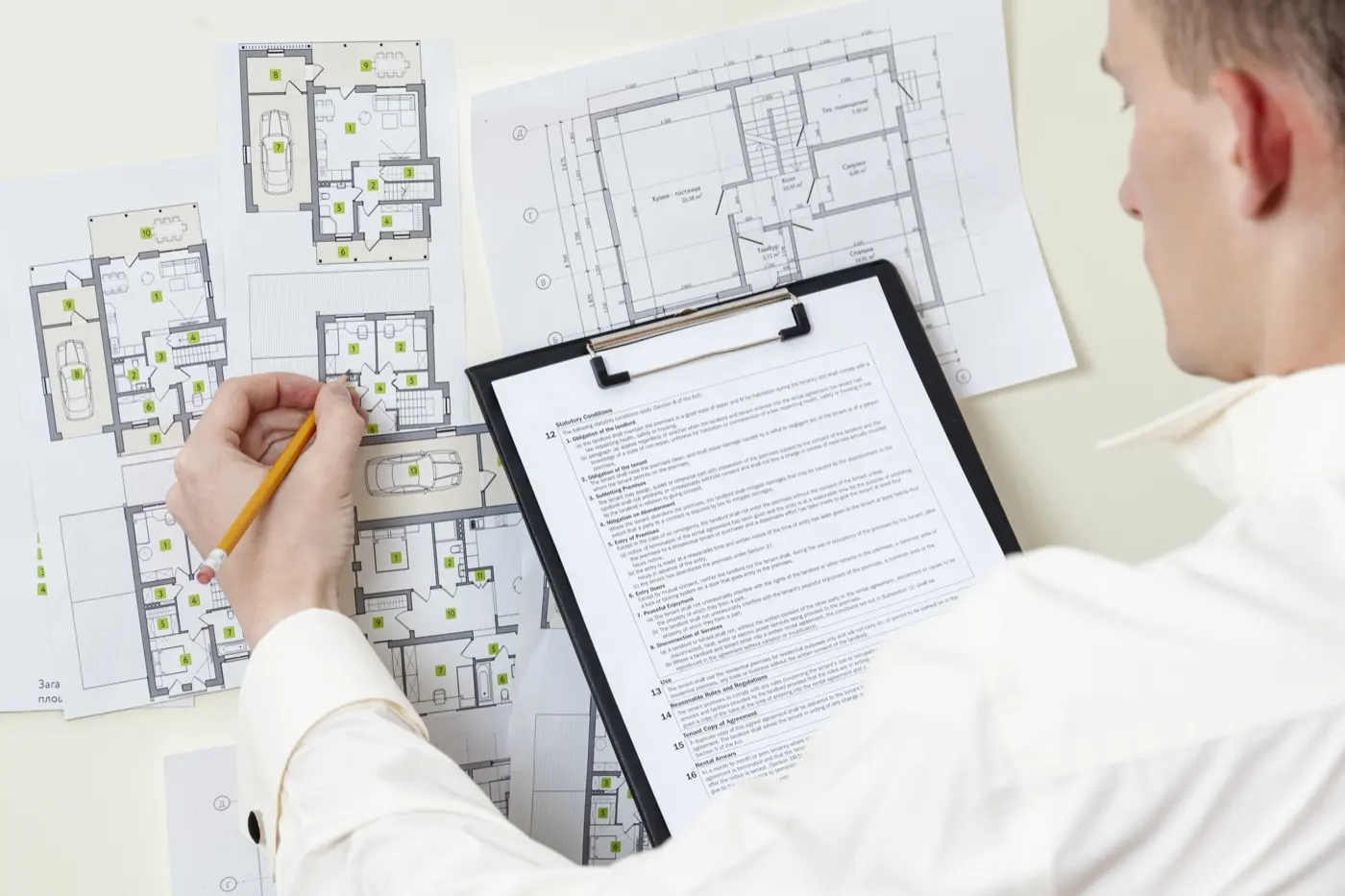 Person filling in a form over house plans
