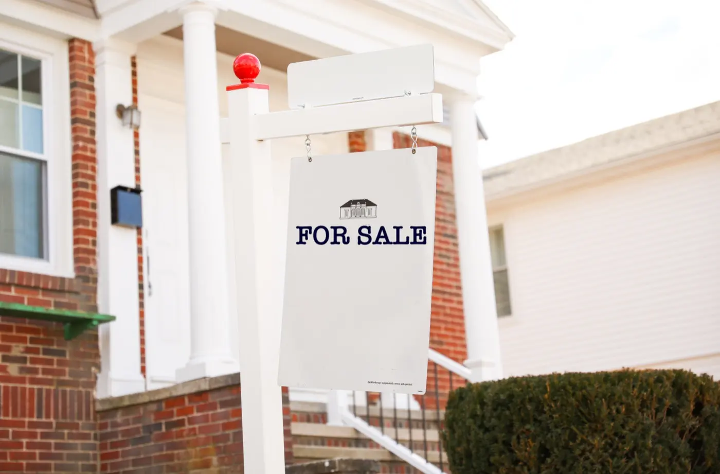 For-sale sign hanging in front of a house