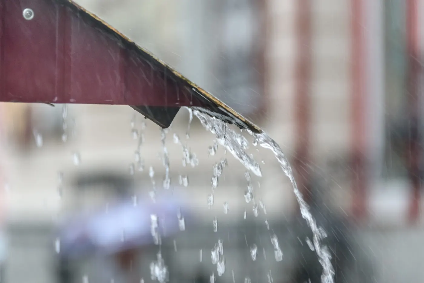 Heavy rain pouring off the edge of a roof in a strong stream