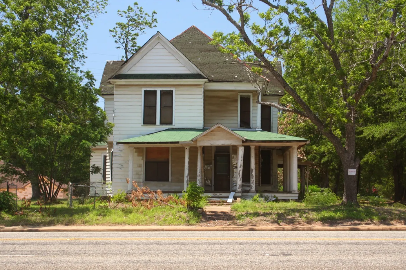 Older two-story frame house with a wide porch in rural East Texas