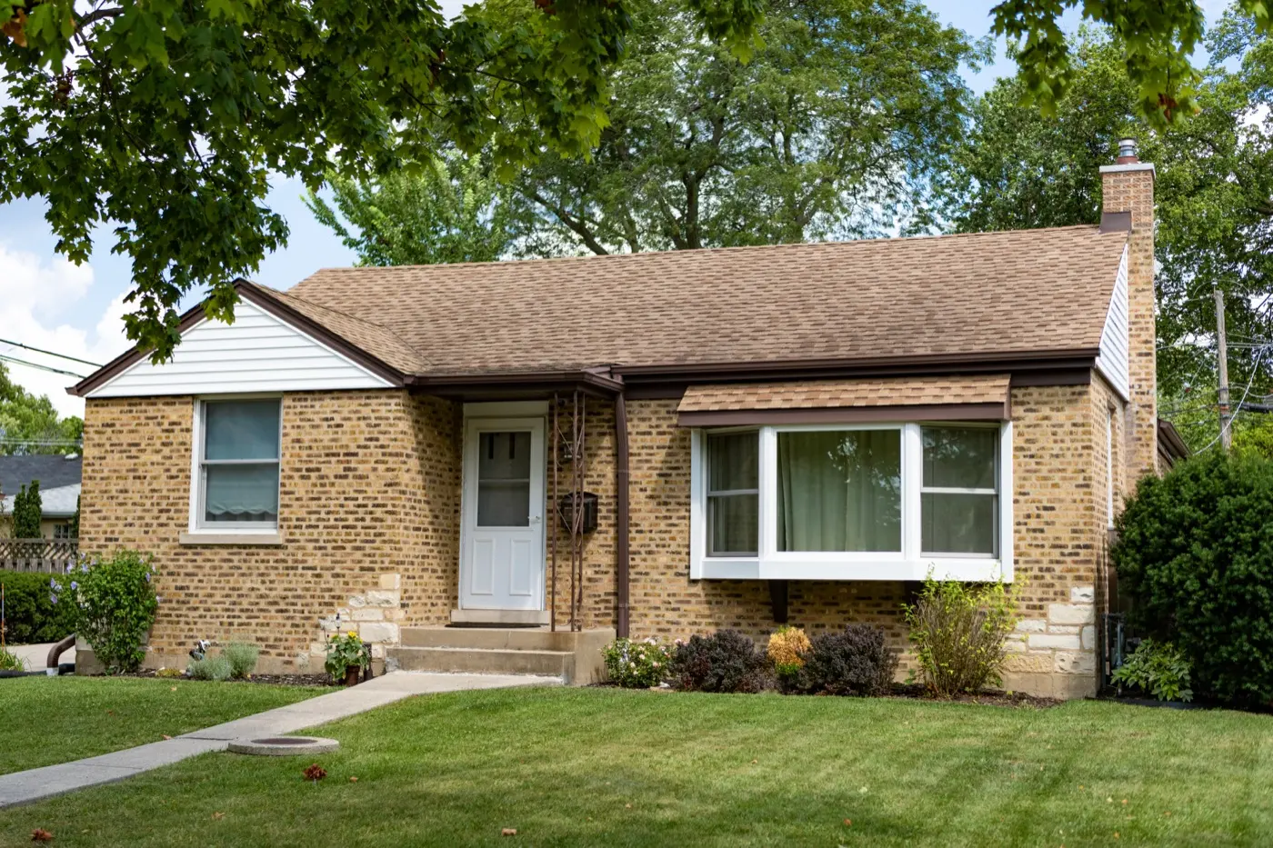 Older one-story brick bungalow with a front lawn